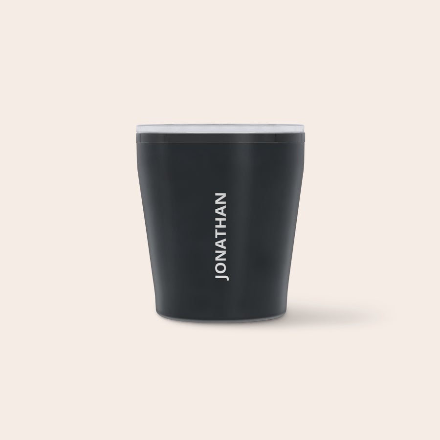 A black personalised travel mug with the name JONATHAN printed vertically in white font on the side