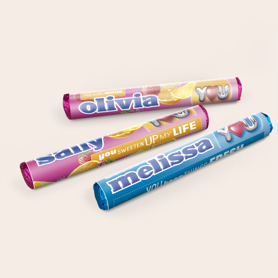 Personalised Mentos Packets Gift Box Three personalized Mentos rolls, two pink with fruit designs and names "Olivia" and "Samy," one blue with "Melissa" and "YOU SWEETEN UP MY LIFE" printed on them.