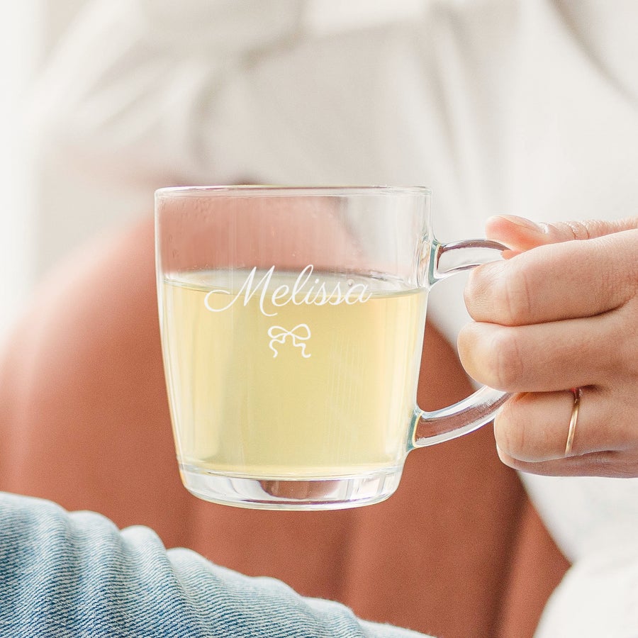 Engraved Glass Mugs Personalised glass mug - Engraved with the name Melissa and a bow design, held in a hand.