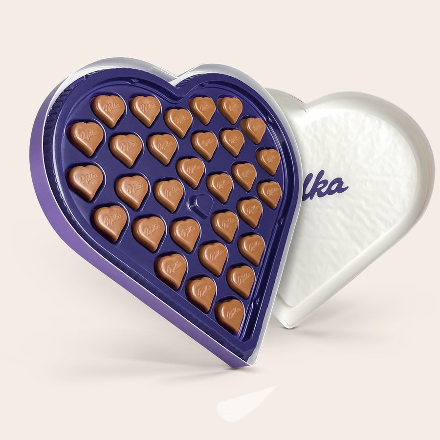 An open personalised Milka heart box with heart-shaped hazelnut chocolates, showing the Milka logo.
