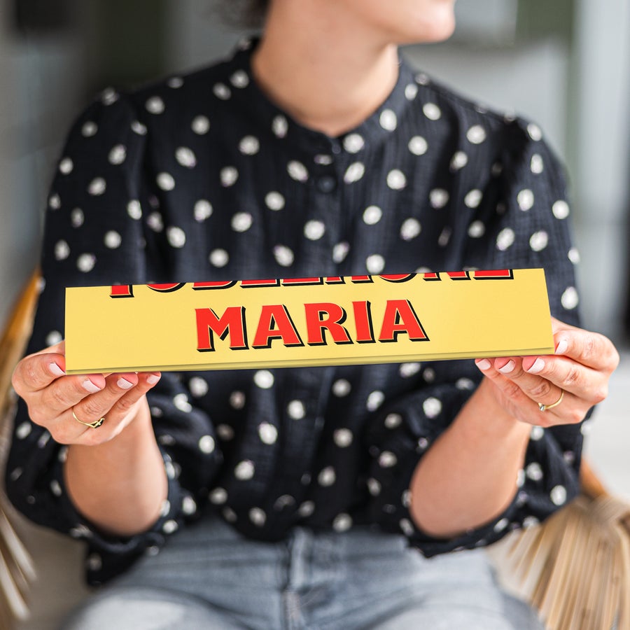 Personalised Toblerone Chocolate Bar A person holding a personalized large Toblerone bar wrapper with the name MARIA printed in red.