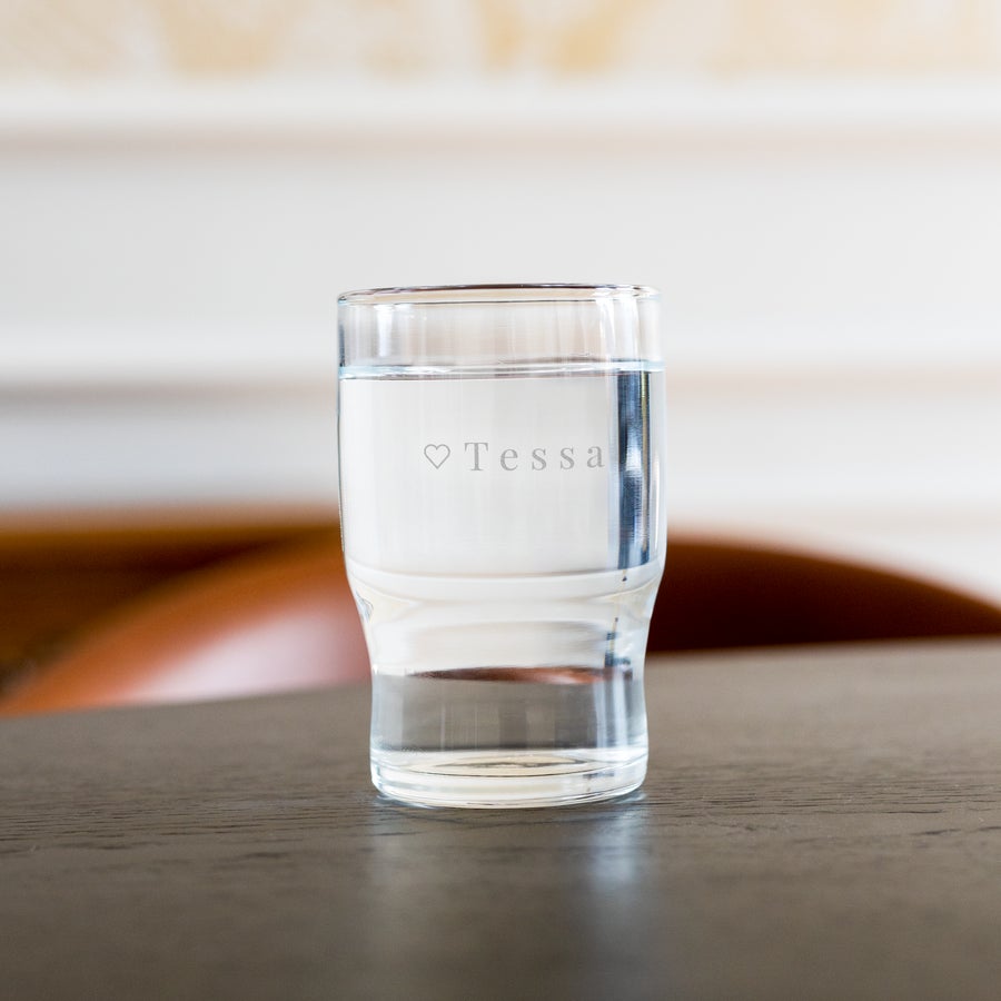 Personalised water glass engraved with the name Tessa and a small heart icon, filled with water