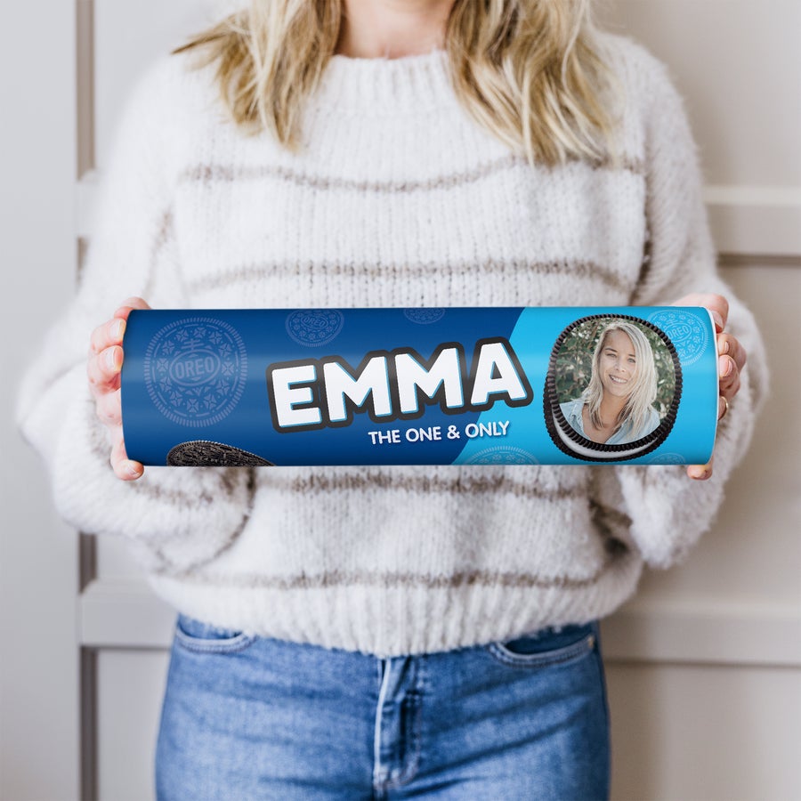 A person holding a blue Mega Oreo Gift Tube printed with the name Emma and a photo of a smiling woman